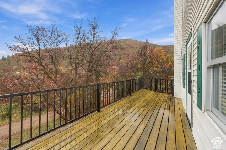 Exterior deck featuring wood-plank flooring, black metal railing, and mountain backdrop