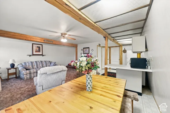 Open-concept interior featuring exposed structural wood ceiling beams, a peninsula counter with cabinet storage, and an integrated ceiling light grid