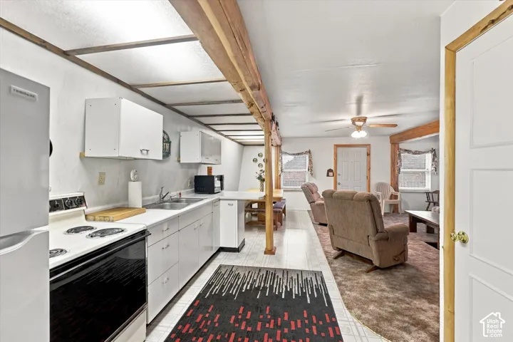 Kitchen featuring white cabinetry, wood-beam ceiling detailing, and light-toned flooring