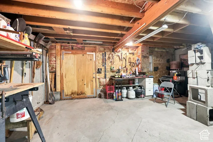 Unfinished basement featuring exposed wood ceiling joists, concrete flooring, and built-in wood cabinetry