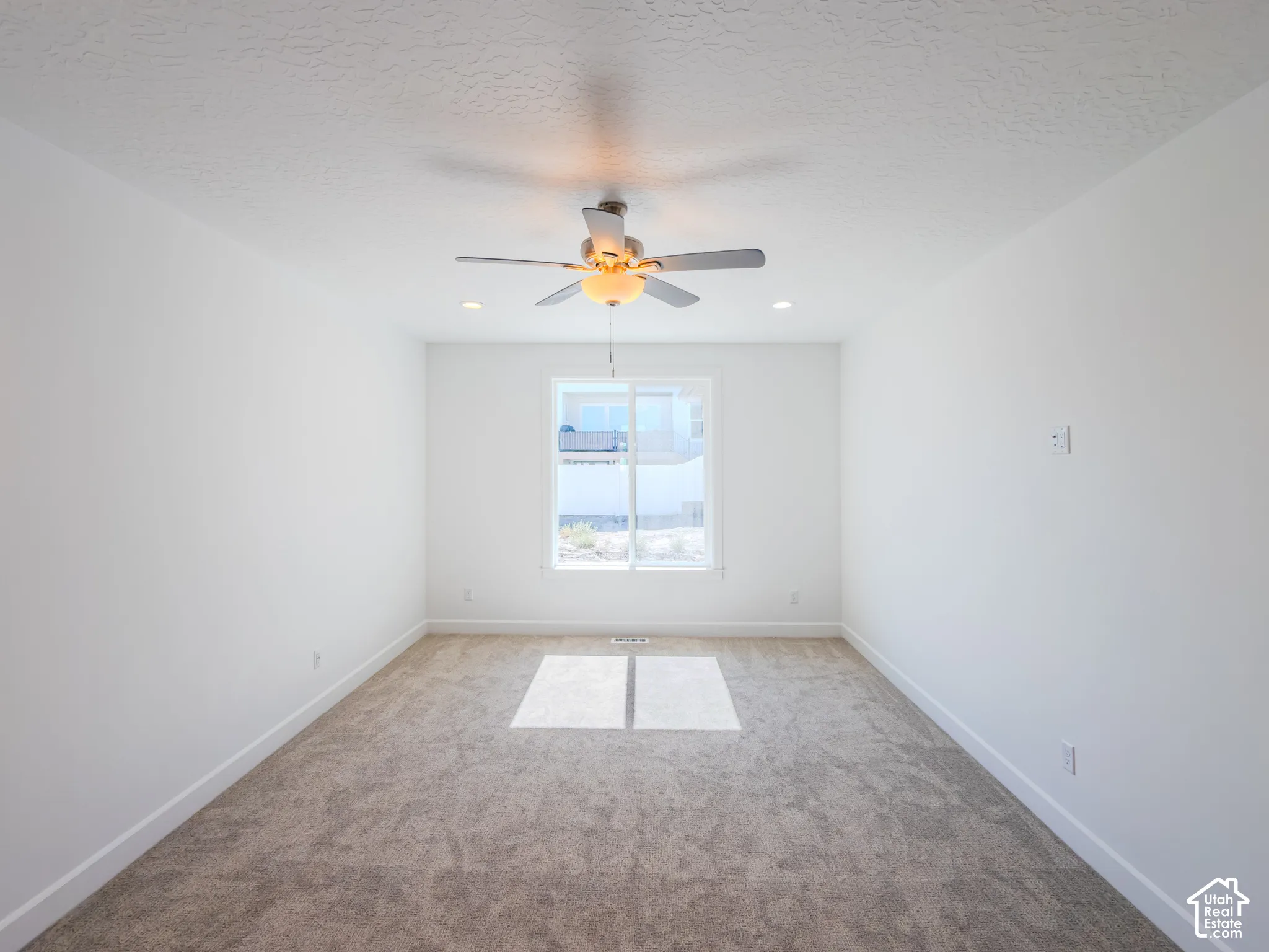 Neutral-toned carpeting, ceiling fan with integrated lighting, recessed ceiling lighting, and a single-pane window