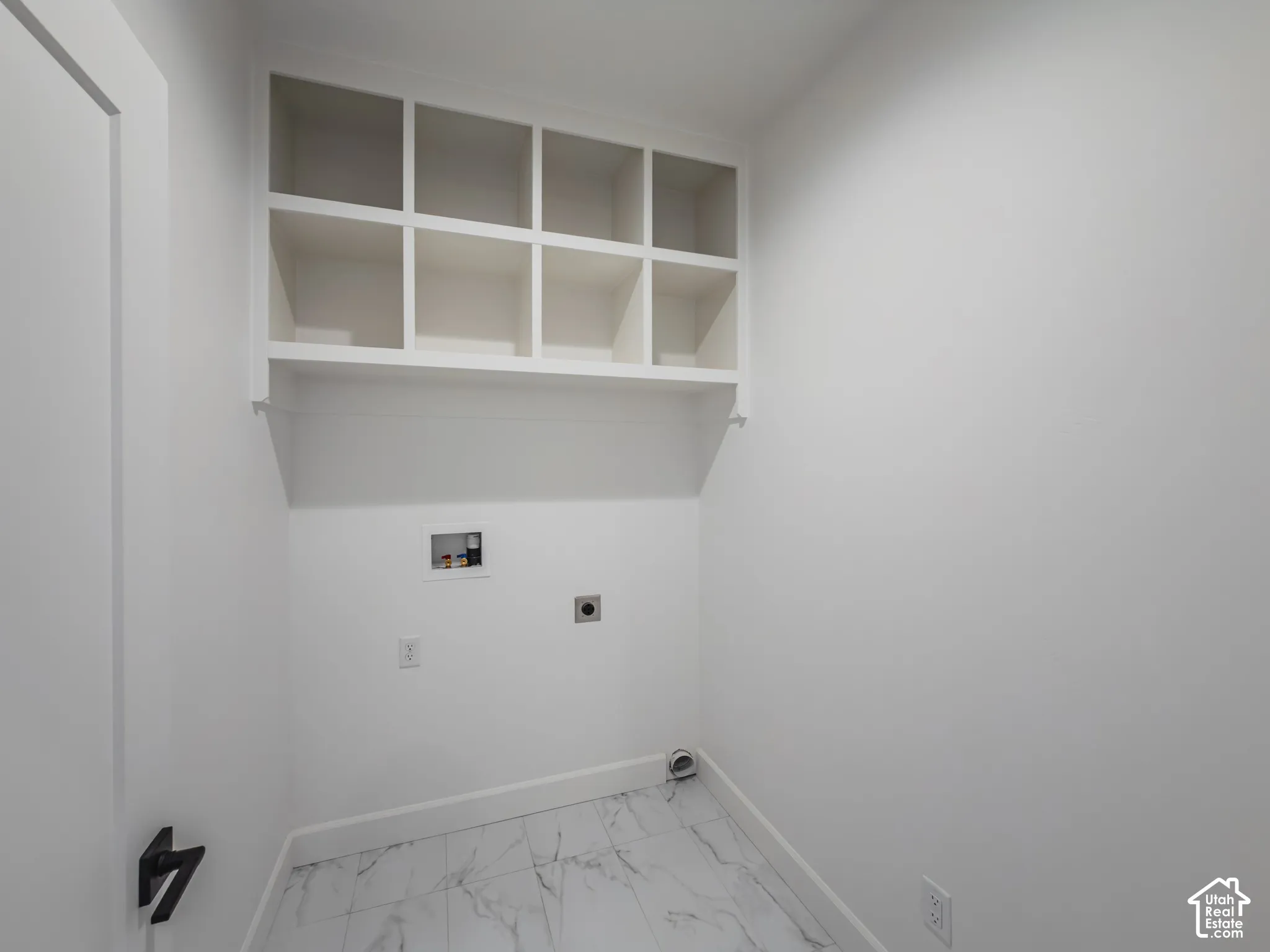 Built-in white cube shelving, stone-finish tile flooring, and matte black door hardware