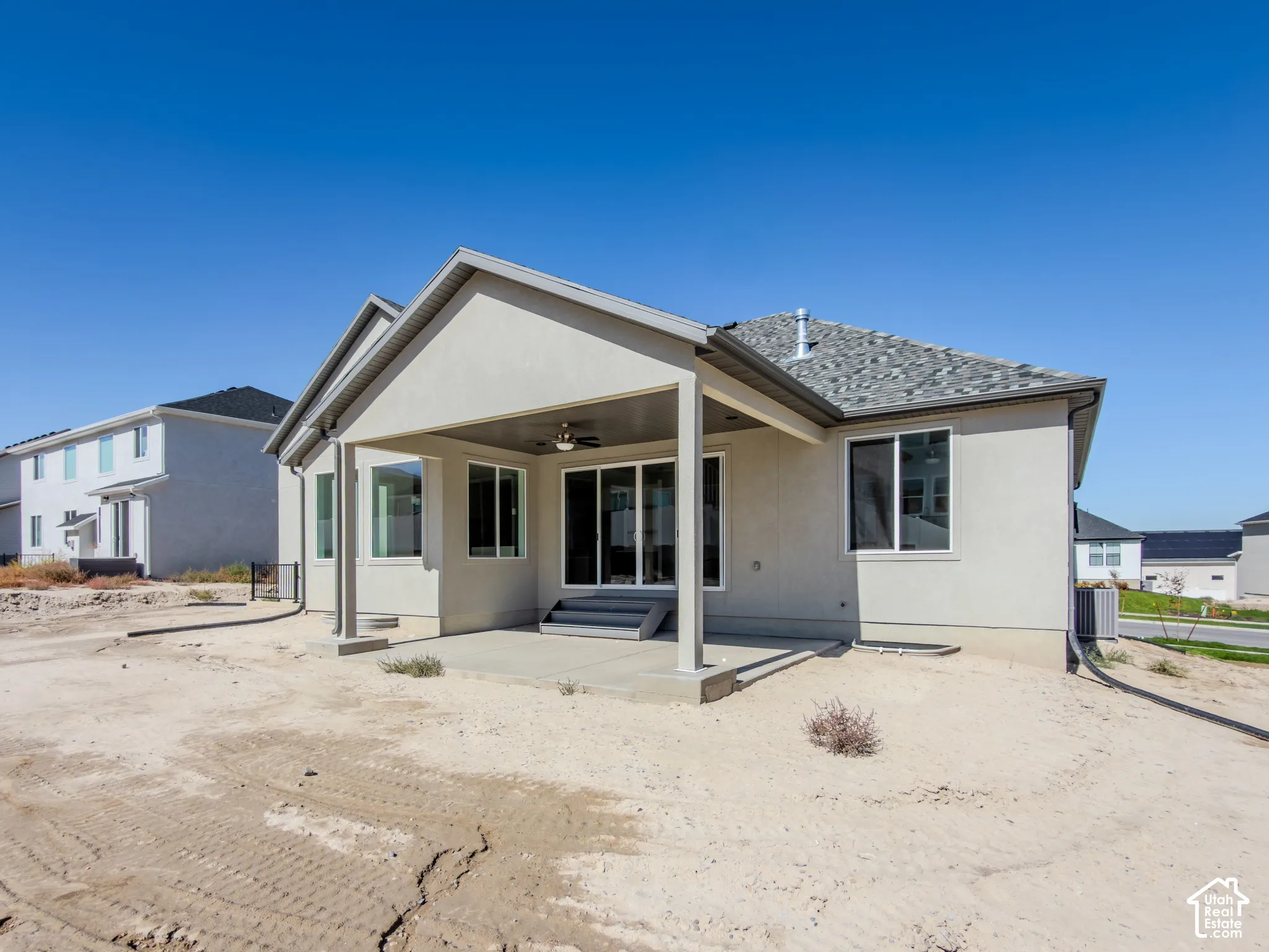 Stucco exterior featuring a covered rear patio, recessed ceiling fan, sliding glass doors, and a shingled roof