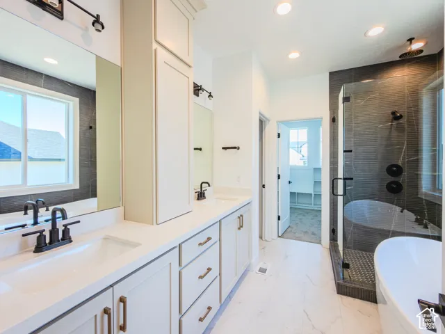 Double vanity with white countertops, integrated sinks, and matte black fixtures, paired with a walk-in glass-enclosed shower, freestanding soaking tub, and tile flooring