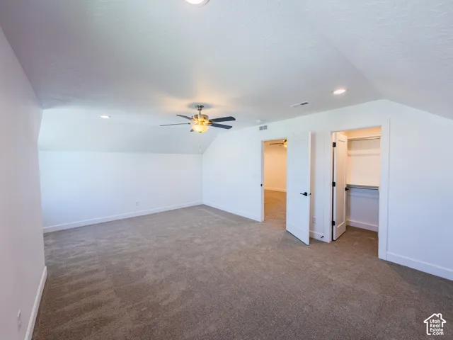 Vaulted ceilings featuring recessed lighting and a central ceiling fan, neutral wall-to-wall carpeting, and a built-in closet with integrated shelving