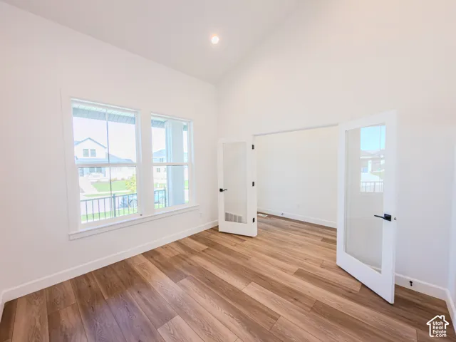 Vaulted ceilings, wood-finish flooring, dual-pane windows, and white-framed French doors with glass panes