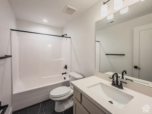 Bathroom featuring a vanity with a light-tone countertop, matte black fixtures, full-width mirror, and a tub-shower combination with surround