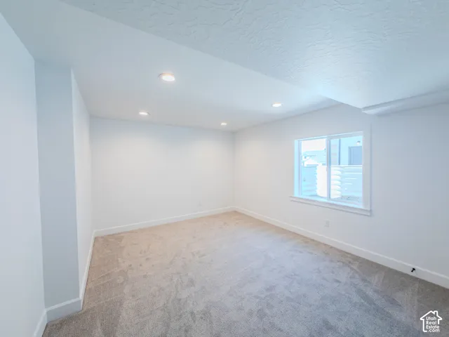 Neutral-toned interior space featuring wall-to-wall carpeting, recessed ceiling lighting, and a window with white trim