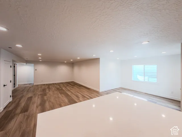 Open-concept interior featuring recessed lighting, wood-finish flooring, a large quartz-topped island, and a horizontal slider window