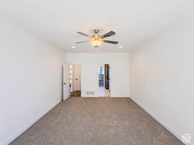 Neutral-toned wall-to-wall carpeting, brushed nickel ceiling fan with integrated lighting, and white interior doors with matte black hardware