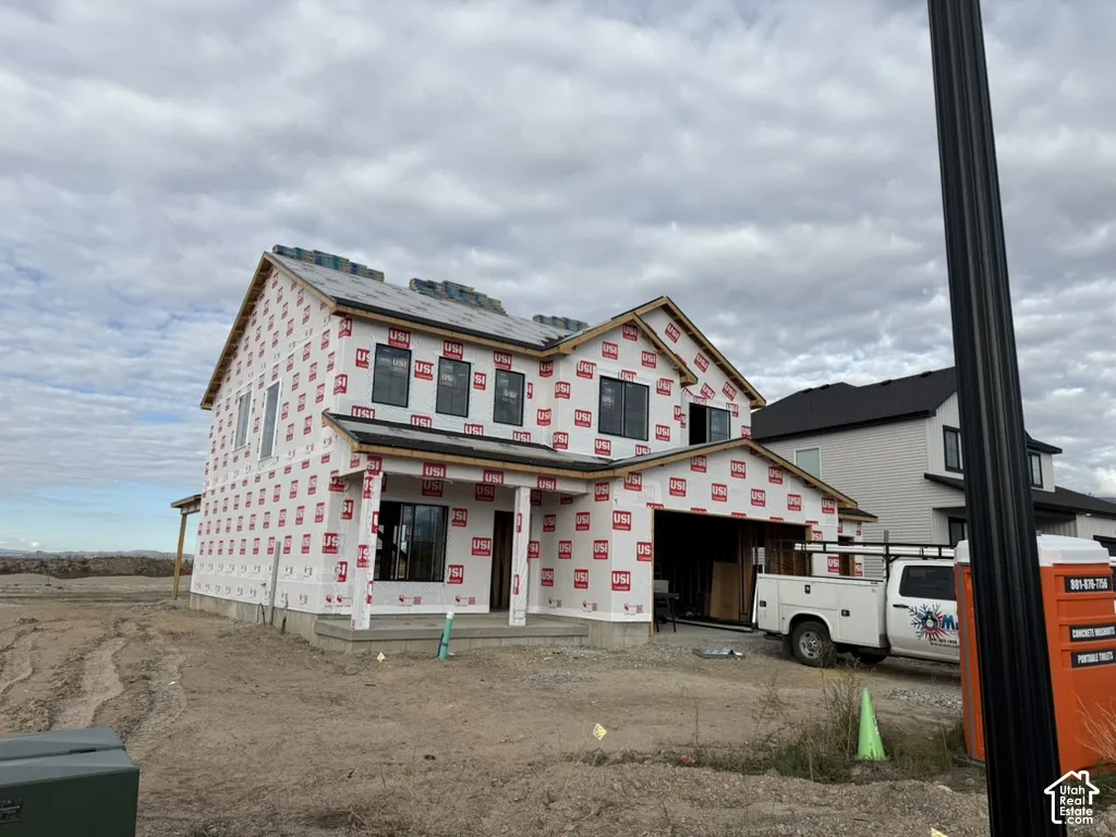 Two-story residential construction featuring a gabled roofline, front-facing garage, and covered entryway