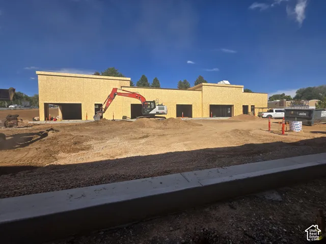 New construction site featuring structural wooden framing, multiple garage bays, and expansive exterior lot space