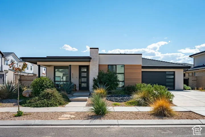 Contemporary exterior featuring smooth stucco siding, warm-toned horizontal wood accents, a stacked-stone chimney facade, a covered entryway, and a multi-panel garage door
