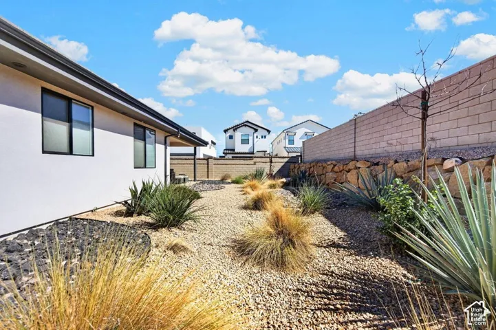 Exterior side yard featuring xeriscape landscaping, decorative rock ground cover, a natural stone retaining wall, and a masonry perimeter wall