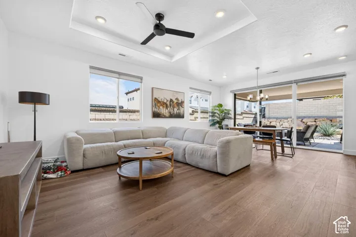 Tray ceiling featuring recessed lighting and a central ceiling fan, wood-finish flooring, and expansive sliding glass doors