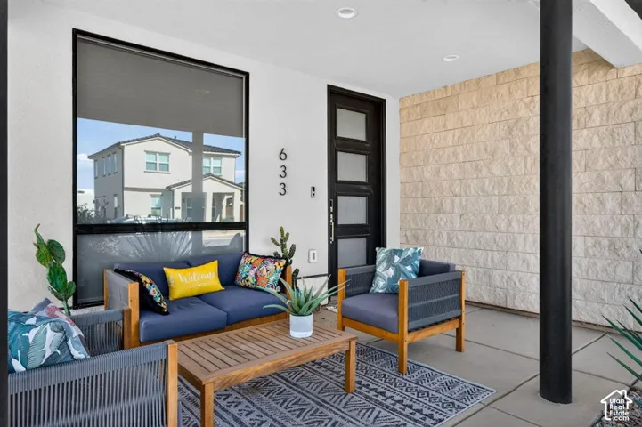 Covered entryway featuring a modern multi-paneled door with frosted glass inserts, a textured stone veneer accent wall, large picture window, and recessed ceiling lighting