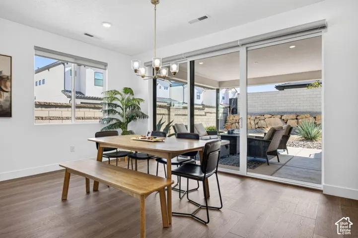 Dining area featuring wood-finish flooring, a multi-light chandelier, sliding glass doors, and recessed lighting
