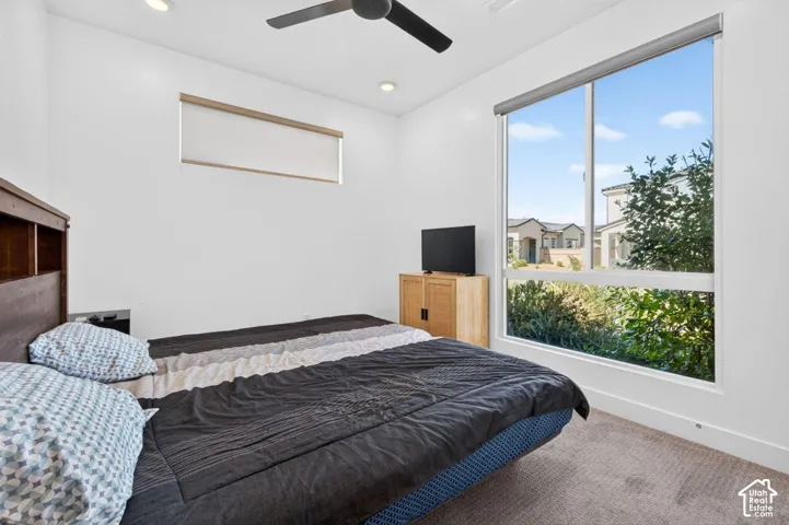 Bedroom featuring large picture windows, recessed lighting, neutral carpeting, and a matte black ceiling fan