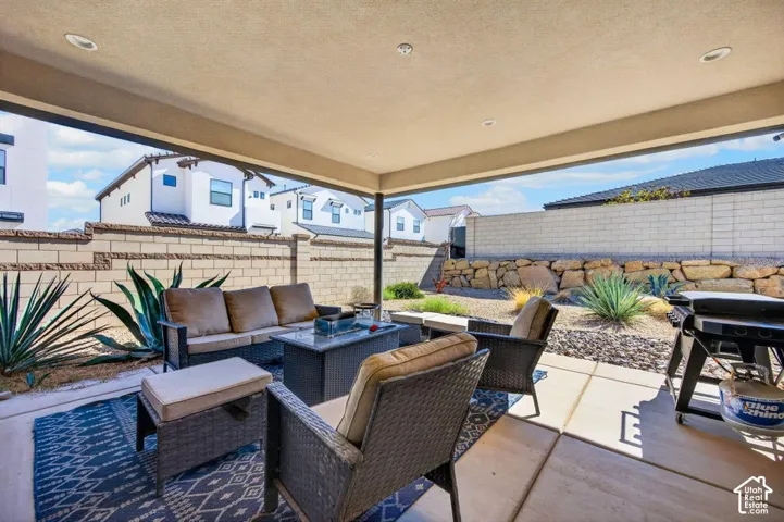 Covered patio featuring recessed lighting, concrete flooring, decorative stone retaining wall, and block perimeter fencing