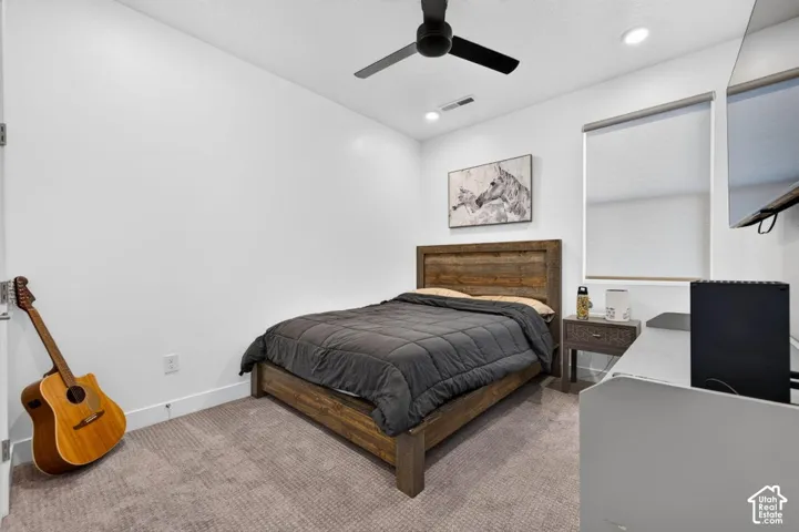 Neutral-toned carpeted flooring, recessed lighting, matte black ceiling fan, and window with installed roller shade
