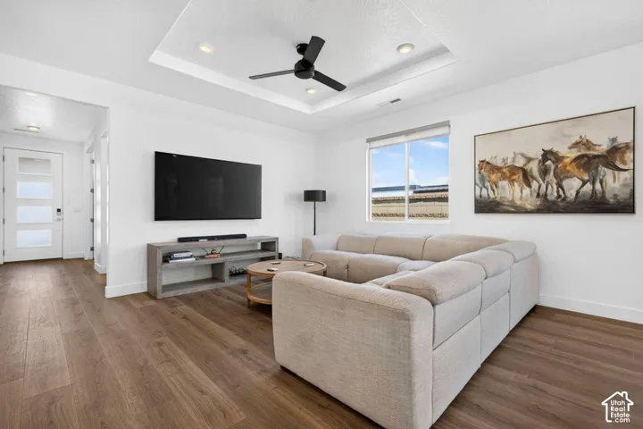 Tray ceiling with integrated recessed lighting, wood-finish flooring, and a contemporary multi-panel glass entry door