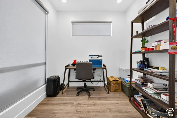 Interior room featuring recessed ceiling lighting, wood-finish flooring, and high-contrast roller window shades