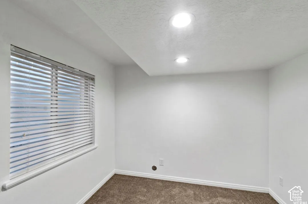 Neutral walls, carpeting, recessed ceiling lighting, and horizontal window blinds