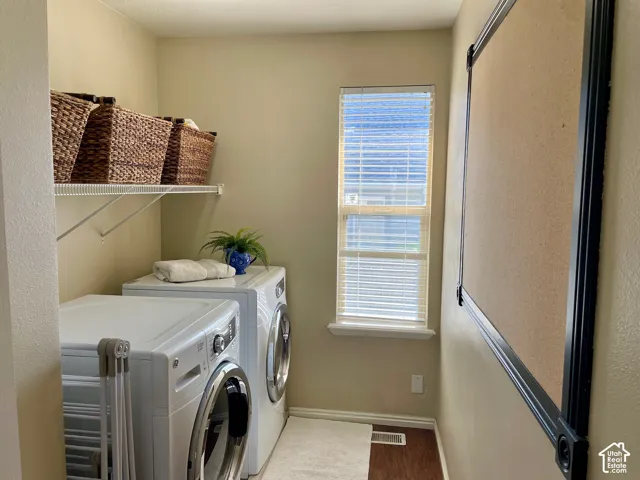 Dedicated utility room featuring wood-finish flooring, a window with horizontal blinds, and a white wire wall-mounted shelving unit