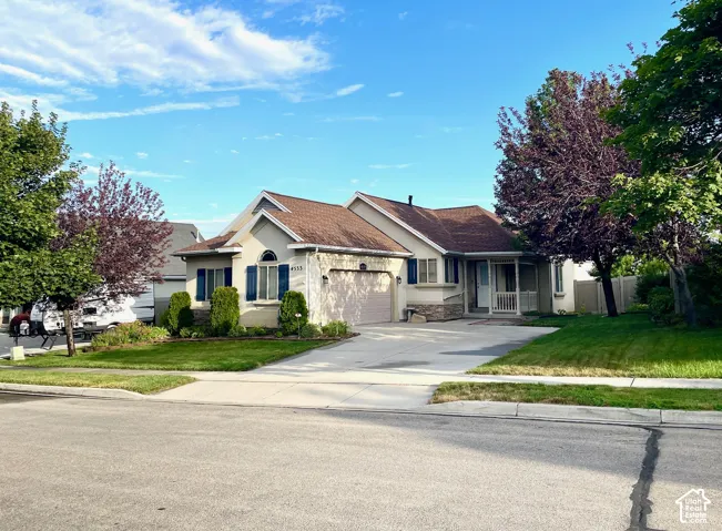 Single-story exterior featuring a stone-accented facade, attached two-car garage, shuttered windows, and a covered front porch