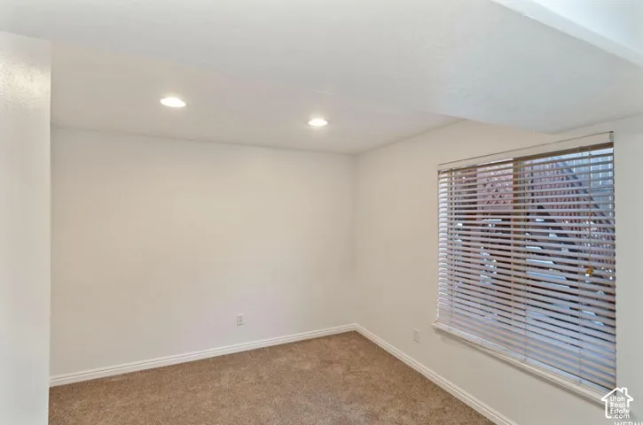 Room featuring neutral carpeting, recessed ceiling lighting, and a window with horizontal blinds