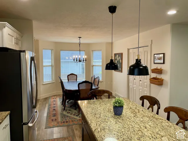 Kitchen featuring an island with stone-finish countertop, wood-finish flooring, dual black pendant lighting, bay windows, and built-in cabinetry