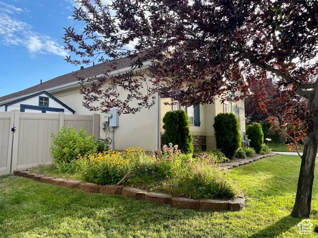 Exterior side yard featuring a stone-accented foundation, built-in storage shed, tiered rock landscaping, and vinyl privacy fencing