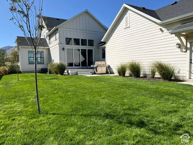 Expansive green lawn, board and batten siding, horizontal siding, large sliding glass doors, concrete patio
