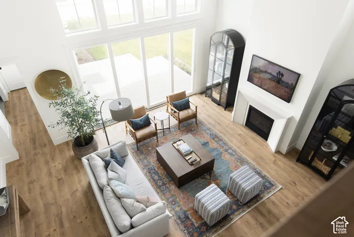 Spacious living area featuring high ceilings, wood-finish flooring, a built-in fireplace, and expansive windows with patio access