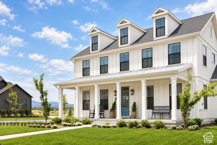 White board-and-batten exterior with black-framed windows, a covered front porch, and a light blue entry door