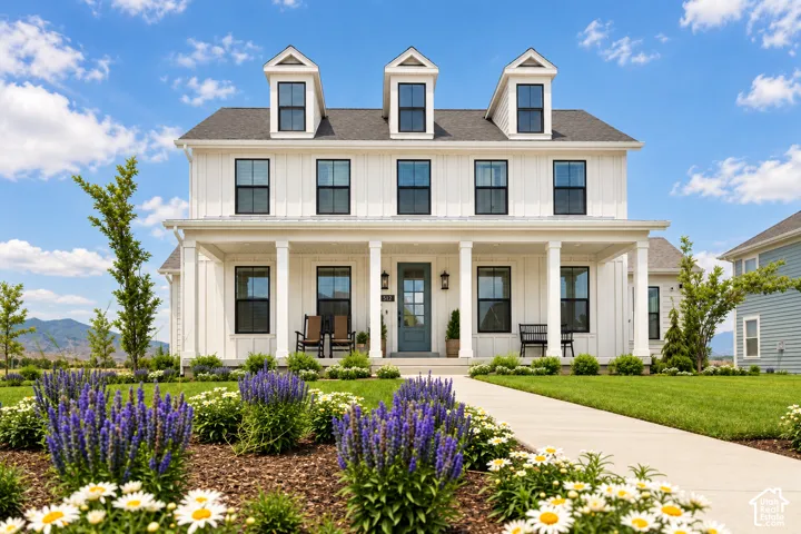 White exterior with black-framed windows, a covered front porch, and three dormer windows