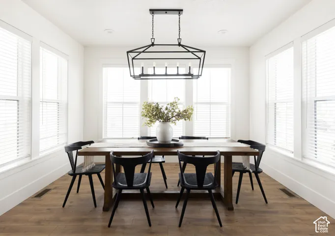 Room featuring four large windows, a black geometric chandelier, and wood-finish flooring
