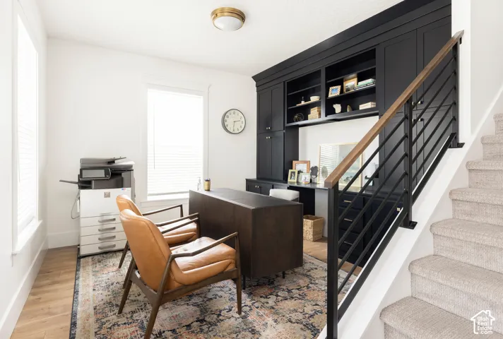 Built-in cabinetry with open shelving, wood-finish flooring, and a modern stair railing with wood handrail