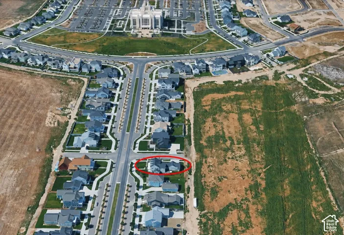 Aerial perspective of a corner lot property featuring a multi-gable roofline, attached multi-car garage, and a concrete driveway situated within a platted residential development