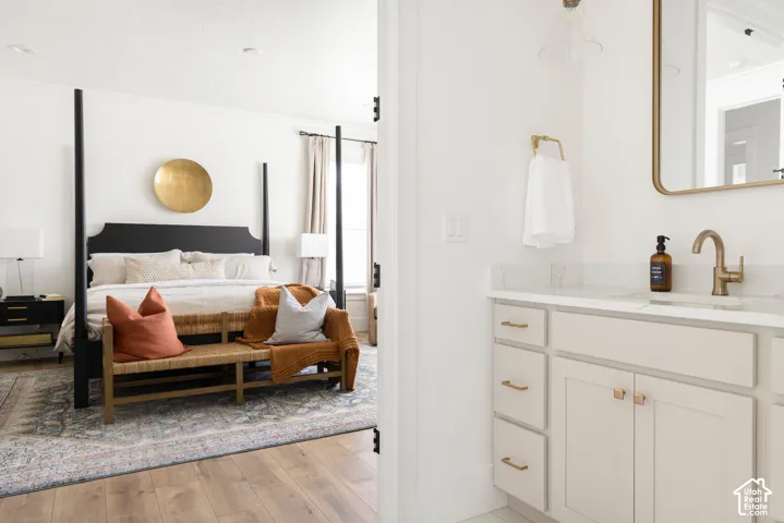 Wood-finish flooring leading to a bedroom with a dark four-poster bed and a window with drapery