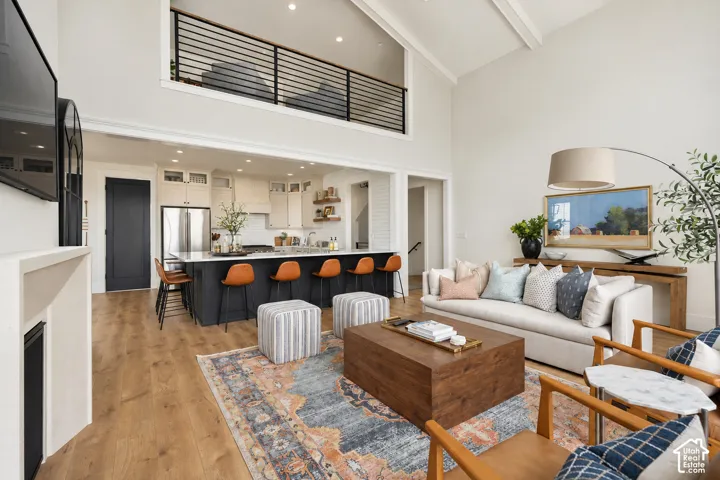 Open-concept living space featuring vaulted ceilings, wood-finish flooring, and a fireplace with a mantel