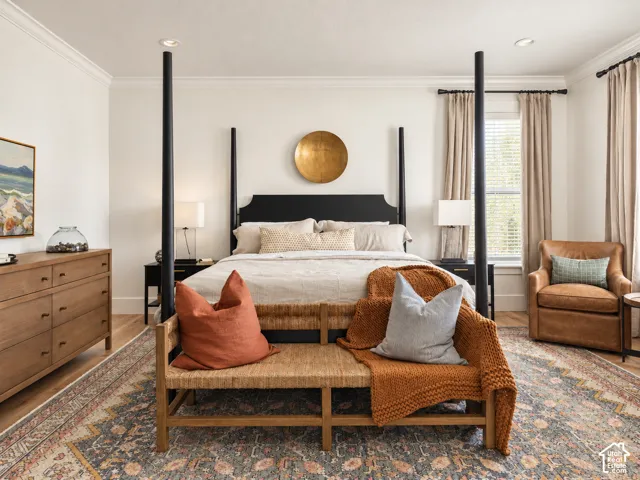 Recessed lighting, crown molding, wood-finish flooring, wood-finish dresser with drawer pulls, and a window with blinds and drapes