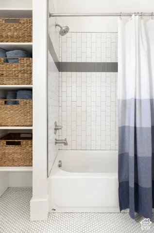 Bathtub with subway tile surround, brushed nickel fixtures, and integrated shelving