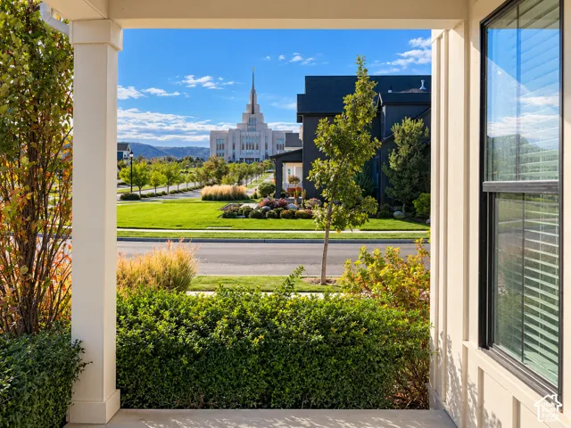 Covered porch featuring square pillars, multi-pane window, and manicured landscaping