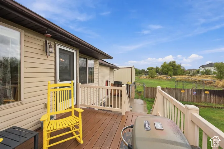 Raised wood-decking porch with balustrade railings and exterior wall-mounted light fixture