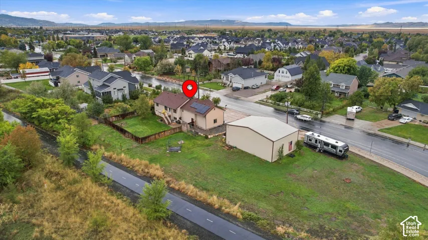 Aerial perspective of a property featuring a detached garage, solar panel installation, fenced yard, and mountain backdrop