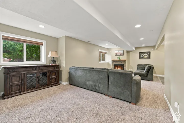Fireplace featuring a stone surround and wood mantel, recessed ceiling lighting, and large windows with exterior foliage exposure