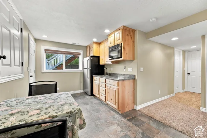 Kitchenette featuring natural wood cabinetry, stone-finish countertops, stainless steel appliances, integrated microwave, and multi-tonal tile flooring