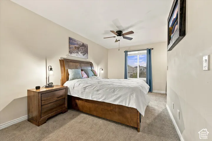 Neutral wall tones, carpeted flooring, and a ceiling fan with integrated lighting