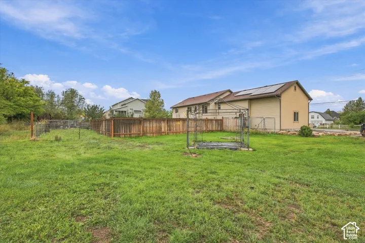 Expansive backyard featuring a wood fence, metal garden trellis, and roof-mounted solar panels
